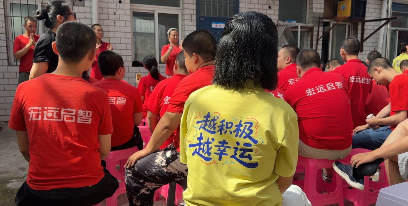 身穿越积极越幸运文化衫的志愿者陪伴孩子们